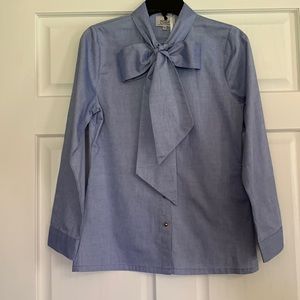 Dainty Jewells blue oxford blouse with tie neck and gold buttons. Size medium.